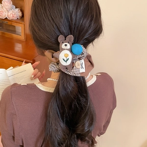 Detail of checkered fabric bow scrunchie with cute corduroy bear worn by a model