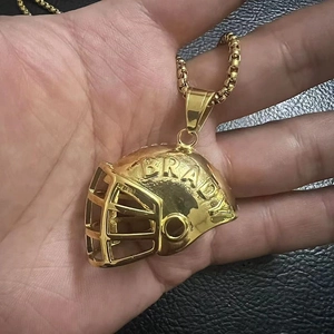 Macro shot of gold-plated football helmet pendant with BRADY engraving and box chain