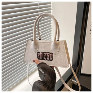 Detail view of a white crocodile pattern handbag featuring a stylish ZMIEBO embroidered patch