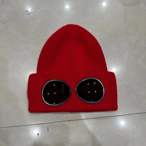 Close-up of a red winter knit hat featuring integrated black goggle lenses and warm fabric