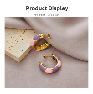 Detail of C-shaped gold-plated stainless steel earrings with purple and pink enamel finish