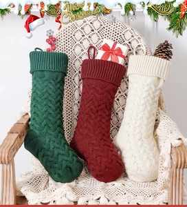 Close-up of three knitted Christmas stockings in red, green, and white on a wooden chair