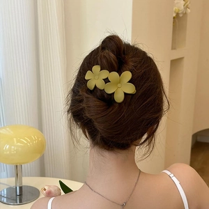 Rear view of a woven hair bun styled with two matte green flower hair clips for women