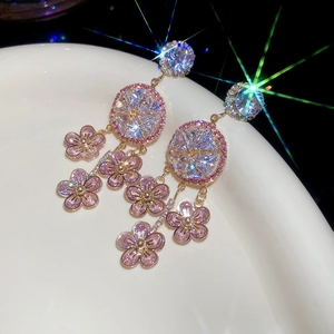Macro shot of gold floral earrings with pink zircon stones and elegant tassel details