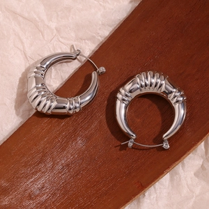 Detailed macro view of silver ribbed hoop earrings with hollow triple-row texture