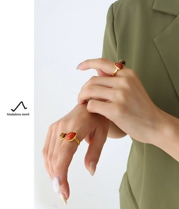 Detail view of gold stainless steel ring with red agate and tiger eye stone on finger