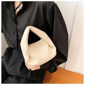 Detail of cream pleated leather handbag featuring soft textured finish and top handle