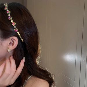 Close-up of elegant emerald green zircon headband and golden stud earrings on a model