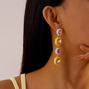 Long drop earrings with colorful enamel geometric shapes and crystals on a model