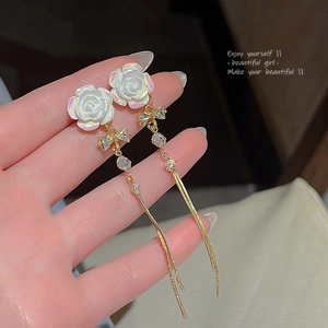 Detailed close-up of long tassel earrings with iridescent roses and crystal bows
