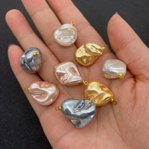 Baroque irregular pearl pendants in various colors held in hand to show actual size