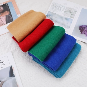 Folded winter knit scarves in camel, red, green, blue and navy on a textured surface