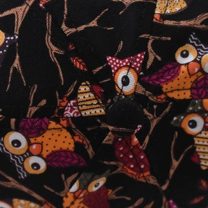 Macro view showing the canvas fabric texture and cartoon owl print on the black baseball cap