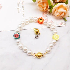 Detail of beaded pearl bracelet with fruit charms and golden magnetic jewelry clasps