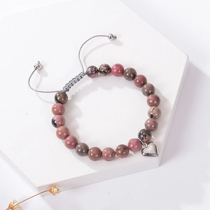 Détail du bracelet en perles de pierre zèbre rose avec breloque cœur sur plateau