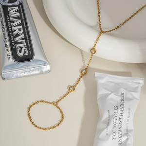Elegant gold finger bracelet with cubic zirconia on a minimalist marble background