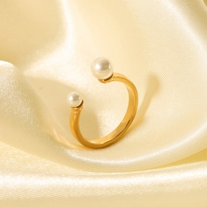Nahaufnahme eines goldenen Perlenrings auf elegantem, beigefarbenem Satinstoffhintergrund