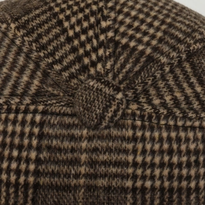 Close-up of a brown plaid wool newsboy cap featuring a decorative top button and texture
