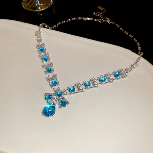 Macro shot of a silver necklace with blue drop stones on a white ceramic tray