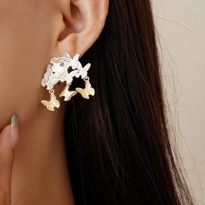 Gros plan de boucles d'oreilles papillon argentées avec pampilles dorées sur un modèle