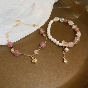 Detailed shot of a pink strawberry crystal heart bracelet and pearl beaded jewelry