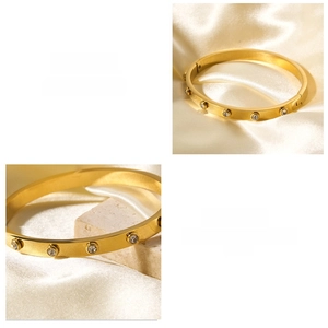Detail view of gold stainless steel bangle with diamond inlay on textured stone background