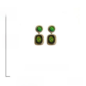 Detail of vintage gold-tone twisted earrings with green resin and 925 silver needles
