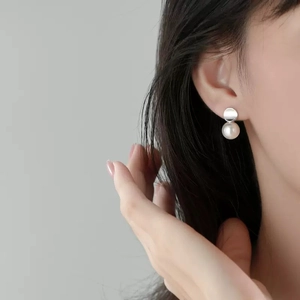 French style silver irregular disc pearl earrings for women showing on model ear
