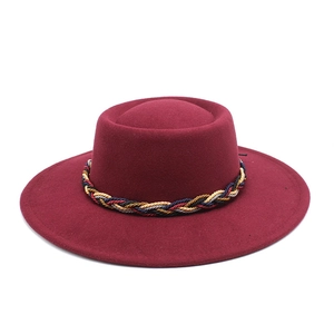 Macro view of burgundy wool felt wide brim hat with a colorful braided rope band detail