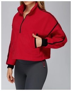 Detail of red fleece half-zip jacket with black trim and grey high-waisted leggings