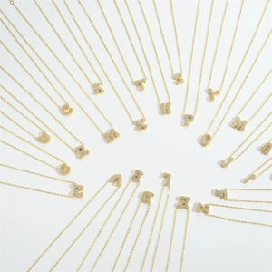 Gold letter necklace set with sparkling cubic zirconia alphabet pendants on white background