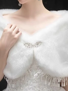 Detailed view of white bridal faux fur stole with rhinestone brooch and fringe trim
