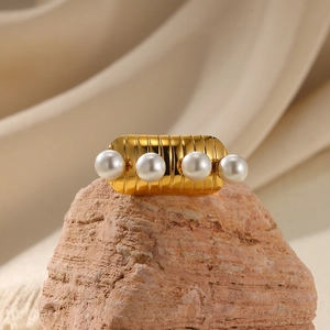 Detail of a golden ribbed ring with four pearls set on a textured stone base