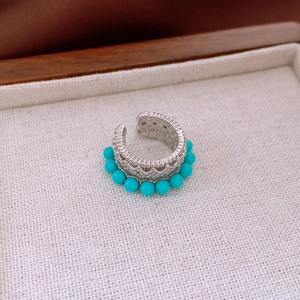 Close-up of vintage hollow silver ear cuff with blue zircon beads on canvas tray