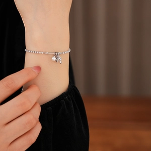 Detail shot of a silver zircon bracelet featuring round white pearls and flower charms