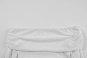 Dettaglio di un top bianco con spalle scoperte che mostra lo scollo a pieghe e il tessuto