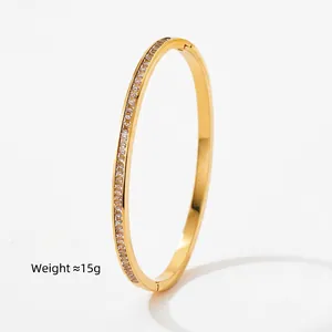 Polished gold stainless steel oval bangle featuring small white zircons and hinge clasp