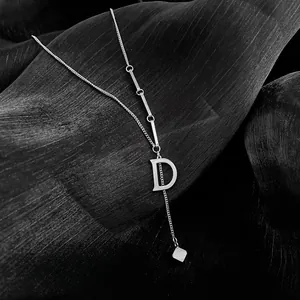 Detailed macro view of silver D letter pendant necklace with minimalist dual chain layers