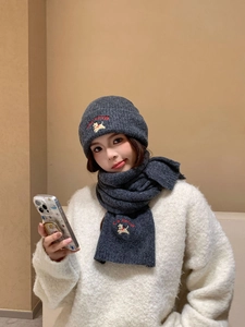 Detailed view of grey knitted hat and scarf set with dog embroidery and letter branding
