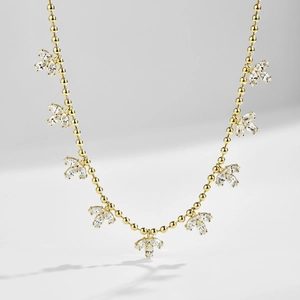 Detail of gold beaded necklace featuring marquise cut gemstone petals in floral clusters