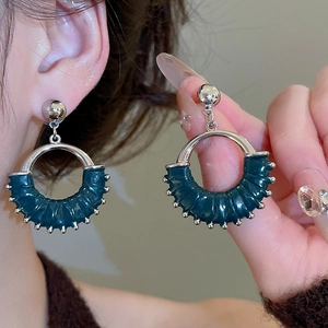 Detail of round geometric drop earring with dark green leather texture and silver beads