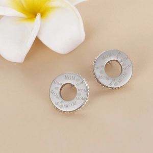 Silver Mother's Day stud earrings with MOM engraving and crystals on beige background