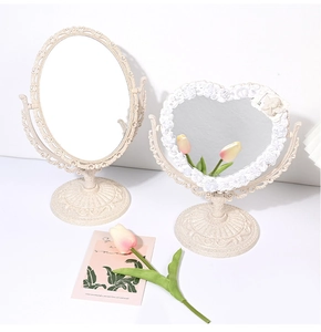 Close-up of heart and oval vintage desktop makeup mirrors with baroque relief patterns