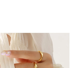 Détail d'une bague dorée ondulée et torsadée au doigt avec texture métal polie