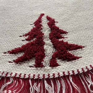 Close-up of 48-inch knitted Christmas tree skirt with 3D cedar patterns and red tassels