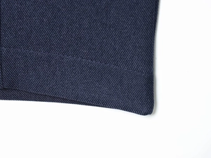 Vue macro détaillée de la texture du tissu sergé bleu marine et coutures précises de l'ourlet