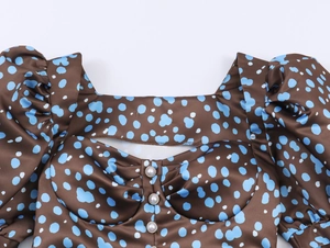 Detail of square neck dress with coffee blue polka dots, pearl buttons and puff sleeves
