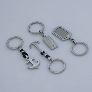 Four silver stainless steel keychains with anchor and geometric pendants on a grey background