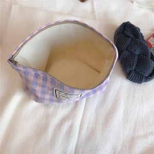 Detail of pink plaid canvas pouch showing metal zipper closure and white inner lining