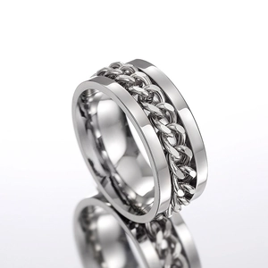 Macro view of silver spinning ring featuring polished cuban link chain detail